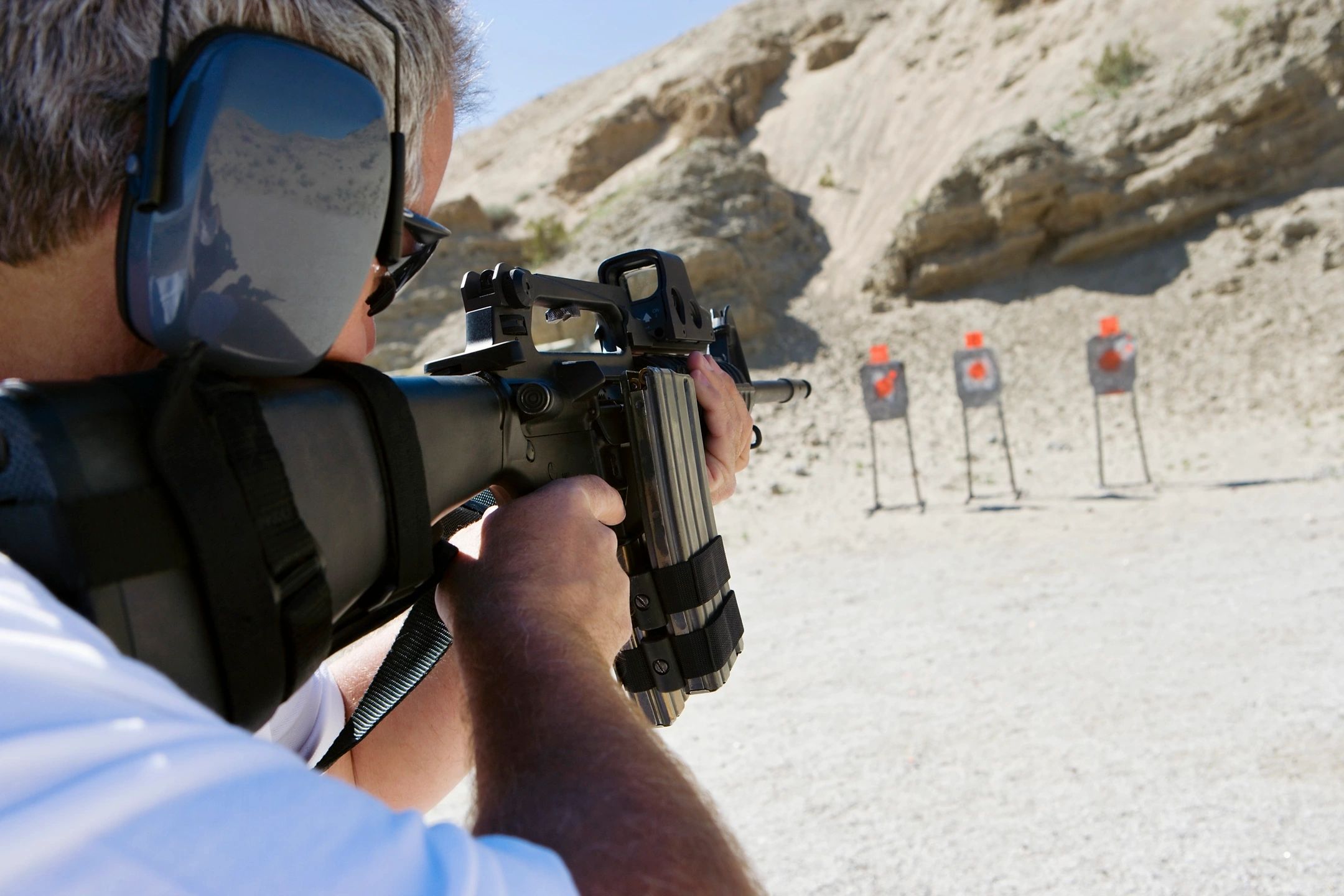 A man fires an AR-15 style rifle at a target.