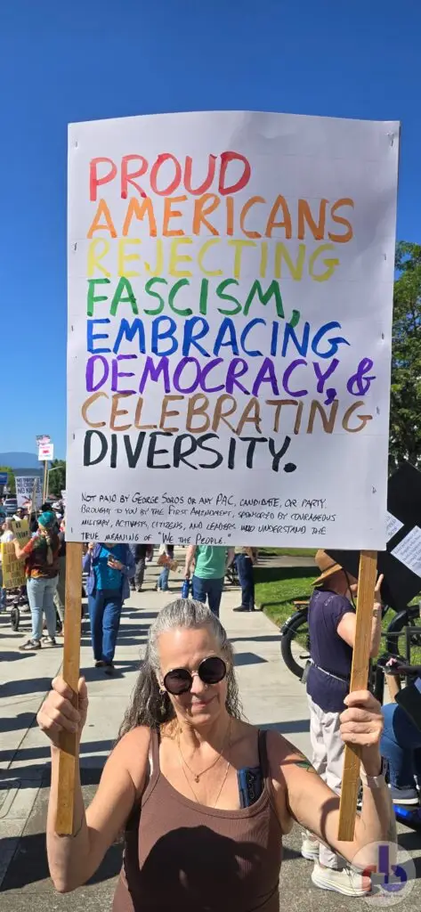Lori's protest sign that reads "Proud Americans Rejecting Fascism, Embracing Democracy, & Celebrating Diversity"