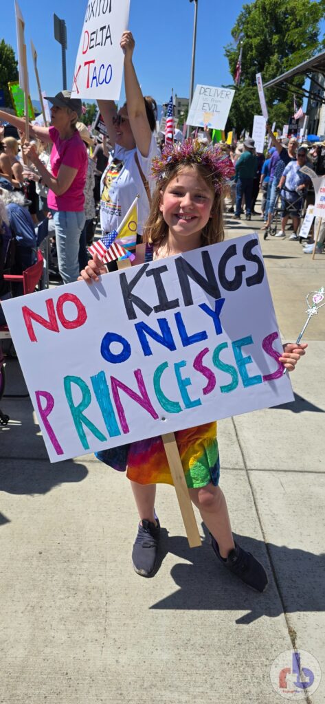 Little girl holding "No Kings Only Princesses" sign